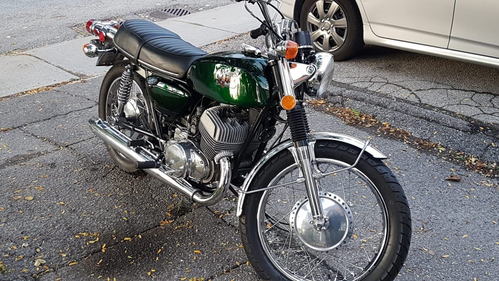 A green vintage motorcycle parked at the curb.