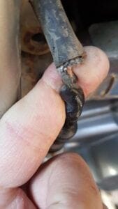 Fingers holding a corroded, frayed wire end