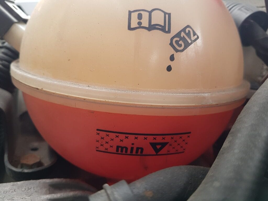 Coolant expansion tank marked G12, with its MIN level line