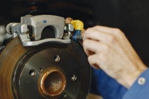 Hands fitting a brake caliper over a brake disc