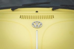 Chrome Volkswagen badge on the hood of a yellow Beetle