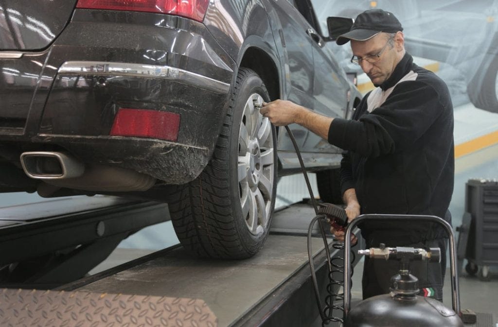 Mechanic adding air to a car tire from an air compressor.
