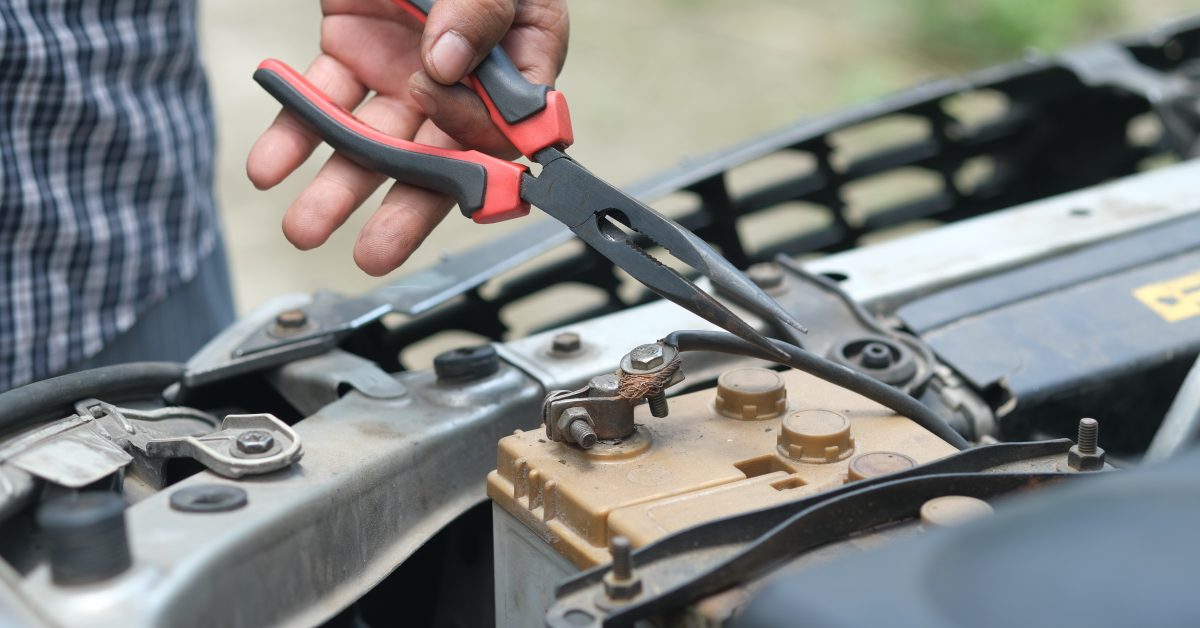 man checking battery cable with pliers