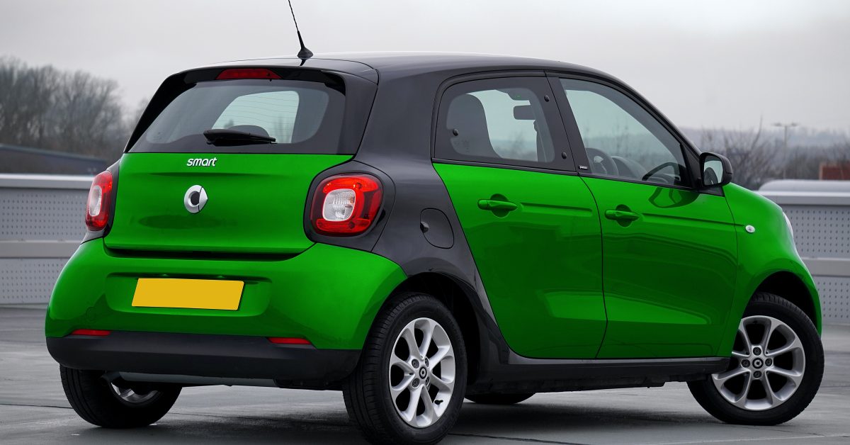 A bright green Smart car parked in a parking lot.