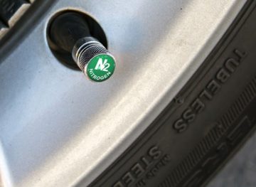 A close-up image of a tire air nozzle with a green nitrogen label on the top of the cap.