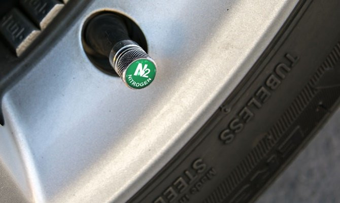 A close-up image of a tire air nozzle with a green nitrogen label on the top of the cap.