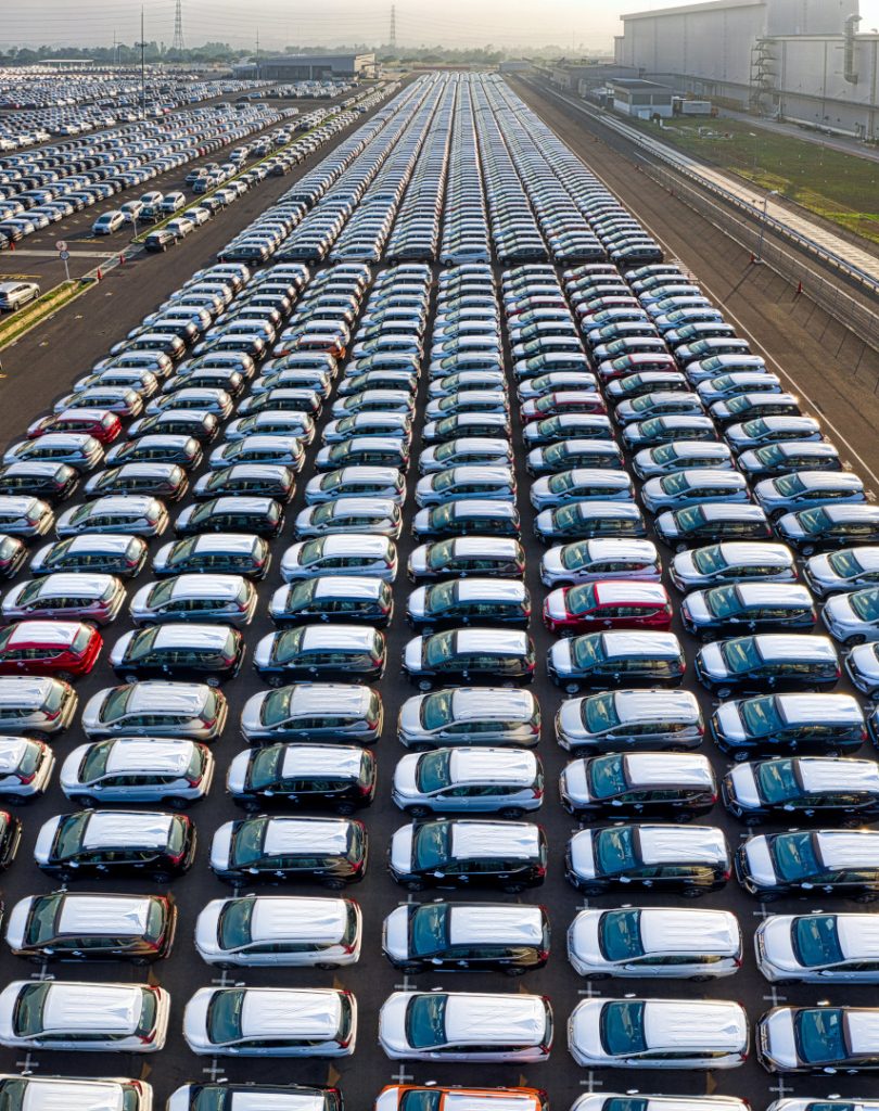 Huge vehicle manufacturing parking lot with hundreds of new vehicles parked in it