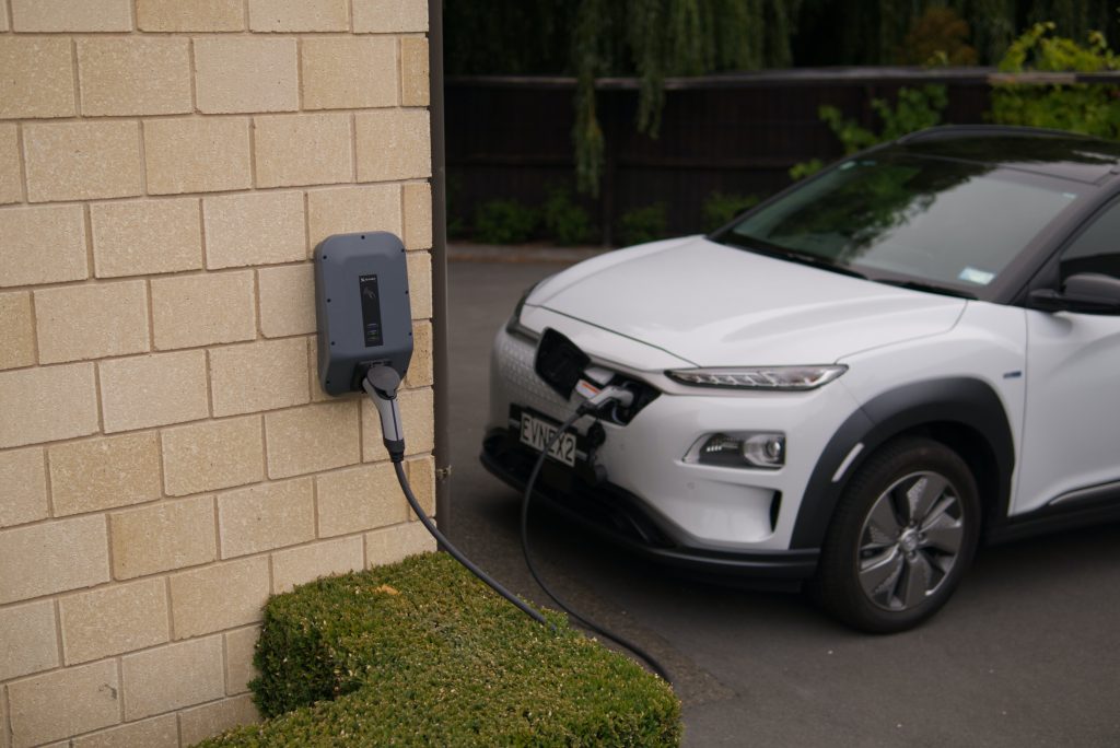 EV vehicle plugged into a charger on the side of a building.