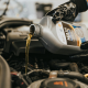 A hand pouring engine oil from oil bottle into oil tank.